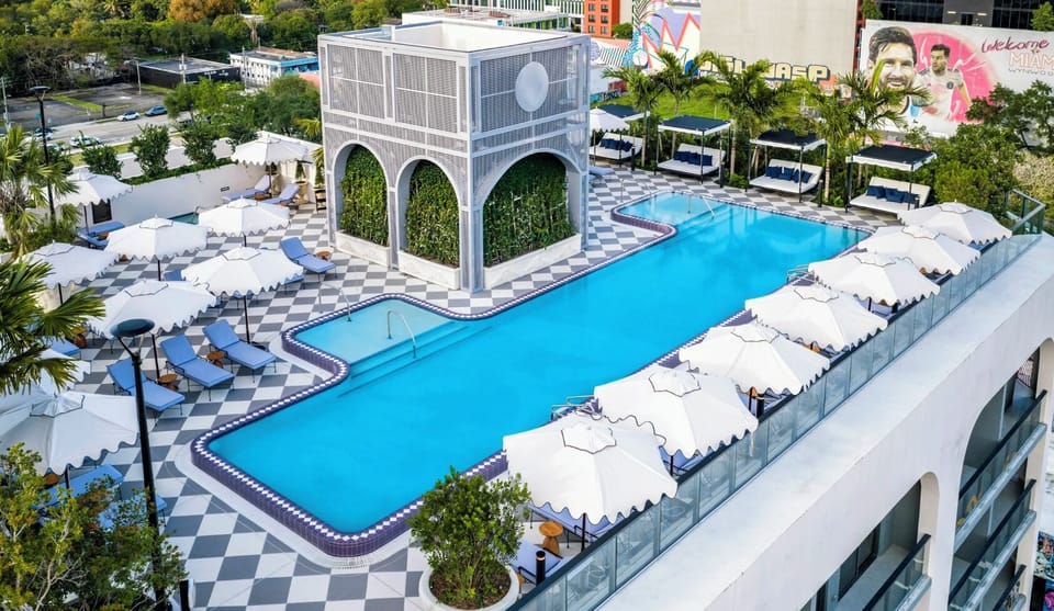 The rooftop pool from above - private cabanas and a sculpted waterline crowning the building.