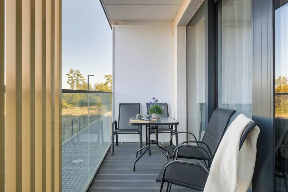 Private balcony with outdoor seating overlooking peaceful surroundings and open views.