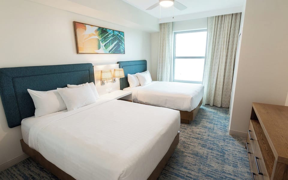Guest bedroom features two queen beds and a TV.