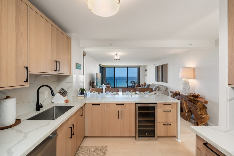 Fully equipped kitchen featuring quartz countertops, stainless steel appliances, and stunning ocean views extending through the living area.