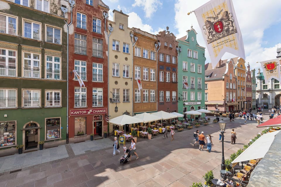 A view of a lively city street surrounded by colorful historic buildings. The area has a vibrant atmosphere.