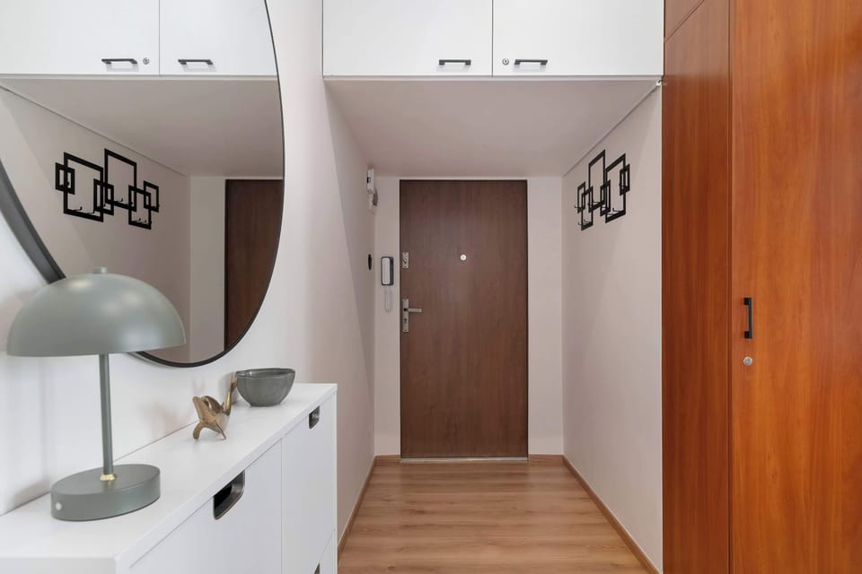 A hallway with wooden flooring, a white cabinet, and decorative lighting. The interior feels bright and welcoming.