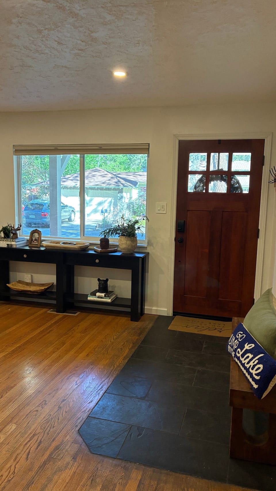Dining area with round table, chairs, built-in window bench, chandelier, wall art, and window.