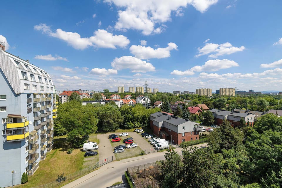 A panoramic view of the neighborhood under a bright blue sky. Green spaces and city buildings create an attractive urban landscape.