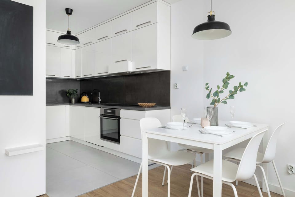 A fully equipped kitchen connected to a dining corner with seating for four. The functional layout is ideal for preparing and enjoying meals.