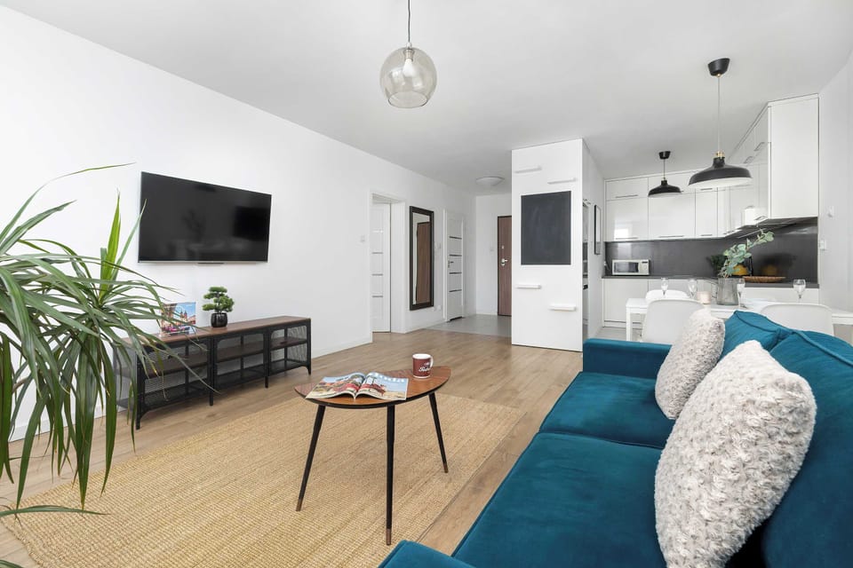 An open-plan room combining the living space and kitchen. Decorative plants and modern furnishings add a pleasant touch to the interior.