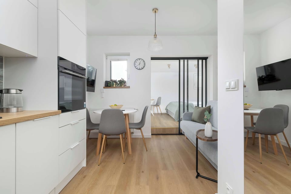 An open-plan interior combines the kitchen with a dining area near large windows. The layout feels bright and spacious.