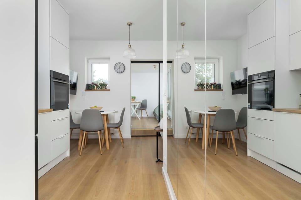 Another view of the kitchen and dining space highlights clean white cabinetry and pendant lighting. The arrangement creates an organized and airy atmosphere.
