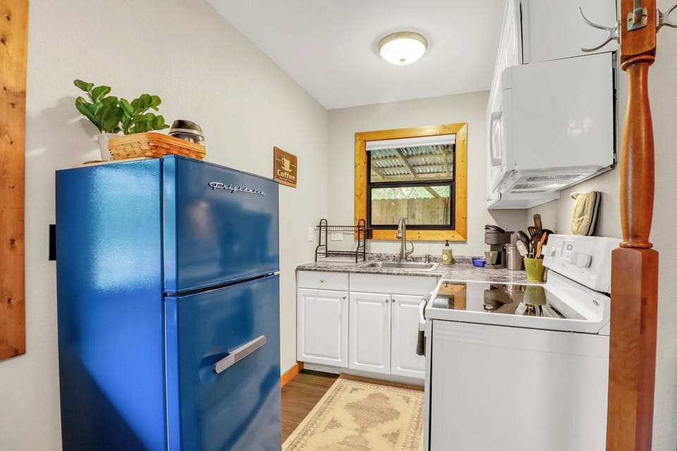 Your charming kitchen features a vintage-style blue refrigerator, granite countertops, white cabinetry, and a cozy atmosphere with warm wood accents throughout the space.