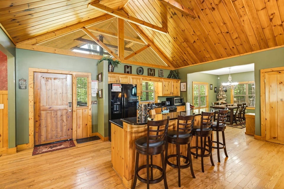 Gather around the warm wood bar where soaring vaulted ceilings and knotty pine create an inviting atmosphere for your mountain escape, with a full kitchen ready for preparing memorable meals together.