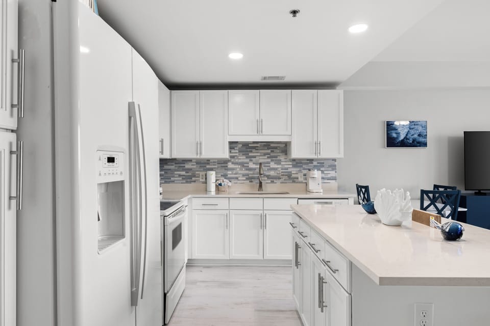 Step into your bright, modern kitchen with crisp white cabinetry, stylish backsplash, stainless steel appliances, and spacious quartz counters—perfect for whipping up your favorite meals during your stay.