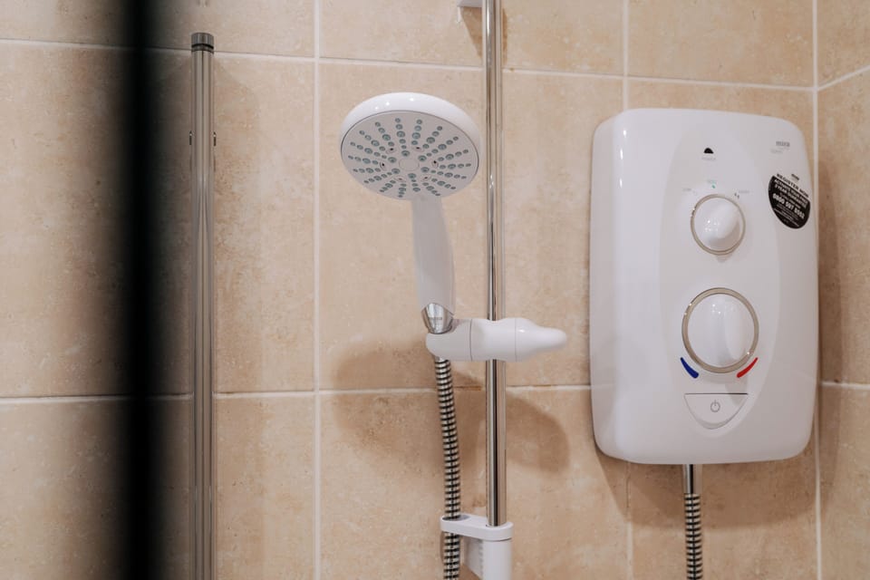 Main bathroom featuring a shower over bath, toilet, and sink, offering the flexibility of a quick refresh or a relaxing soak after a day exploring Liverpool.