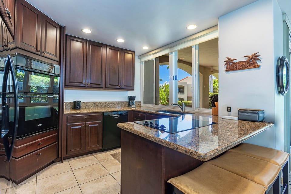 Cook your favorite meals in this fully-equipped kitchen featuring granite countertops, rich wood cabinetry, modern appliances, and a convenient breakfast bar.