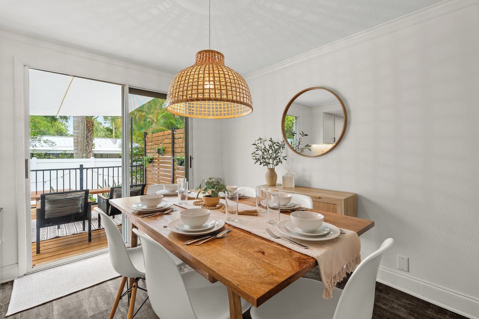 Gather around this inviting dining table, set for memorable meals beneath a warm woven pendant light. Natural tones and views of the tropical balcony create your perfect retreat.