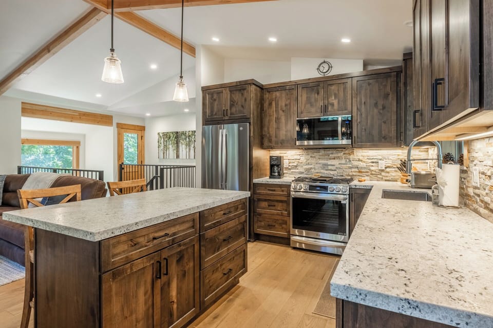Picture yourself preparing meals in this beautifully appointed kitchen with modern appliances and rustic charm, where exposed beams and warm wood create a welcoming atmosphere for your mountain getaway.