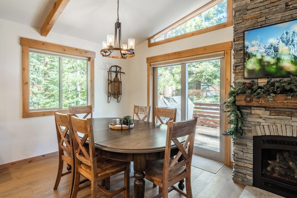 Gather around the dining table for meals with views of the forest and mountains. The fireplace adds warmth while natural light fills your space.