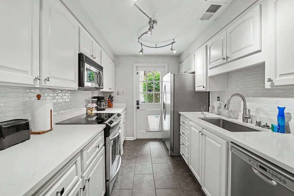This bright white kitchen features sleek modern appliances, creating a stylish and functional space for every meal!