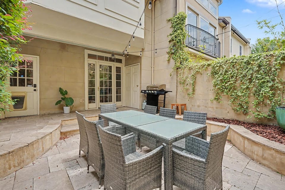 Relax on the inviting patio surrounded by lush plants and comfortable outdoor seating, perfect for enjoying the fresh air!