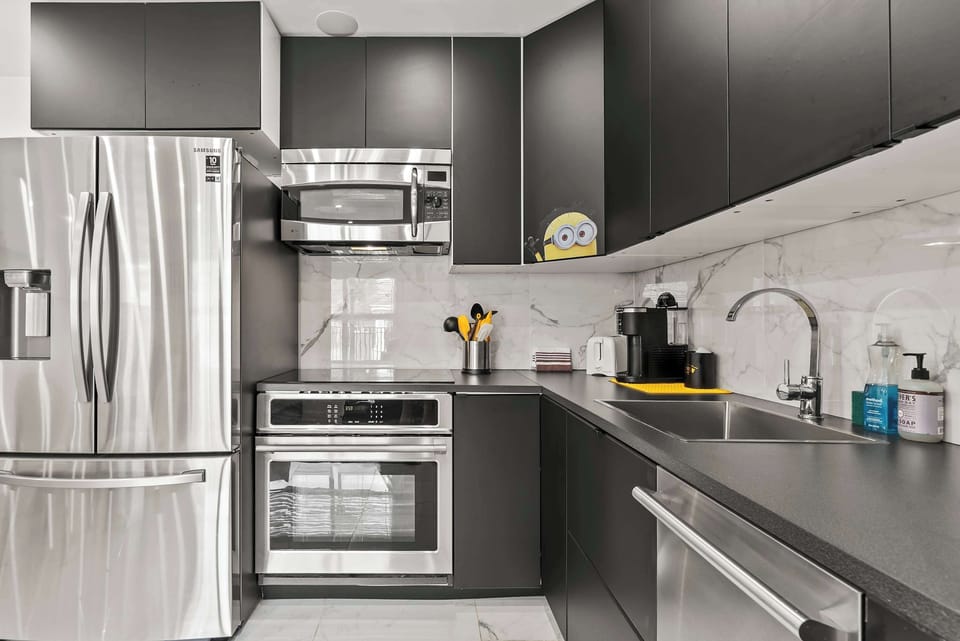 Sleek kitchen corner w/ stainless steel appliances & dark cabinetry for a modern, polished look.
