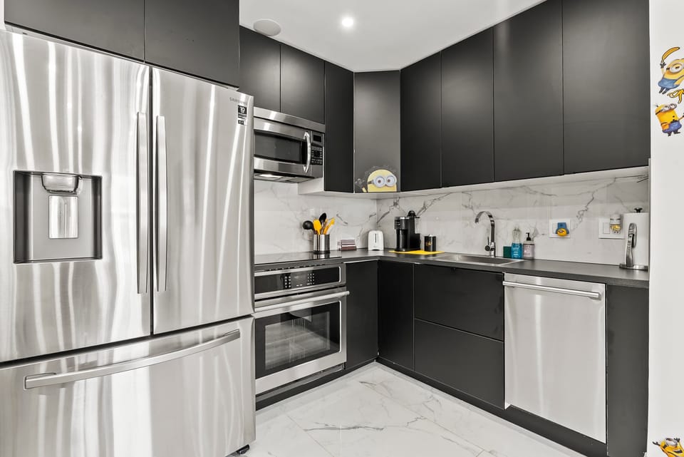 Modern kitchen w/ stainless steel fridge, built-in microwave, & sleek dark cabinetry.
