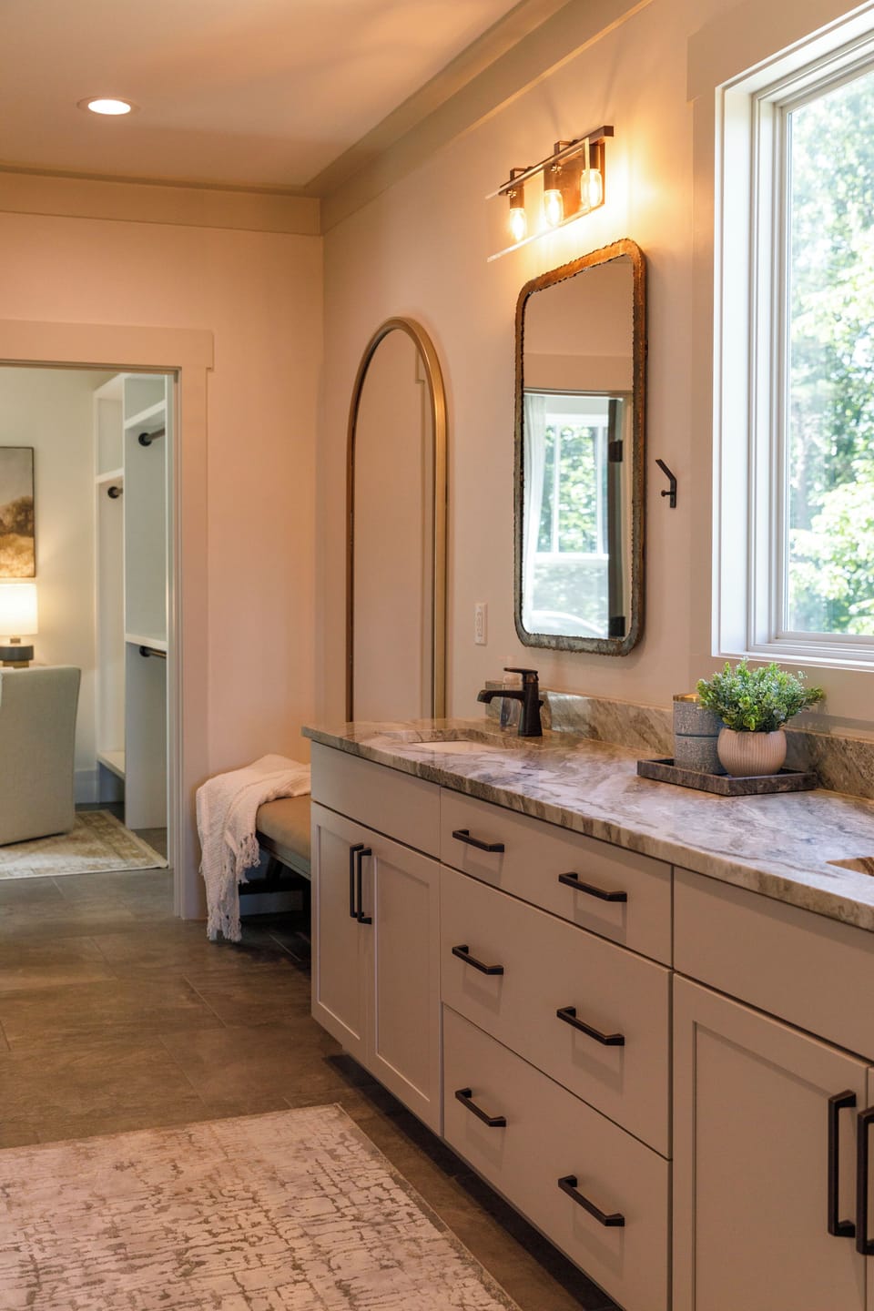 Marble vanity in the primary bath with a walk-in closet and forest views