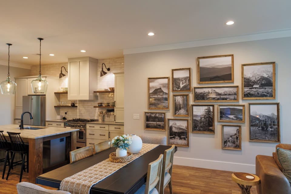 Open chef's kitchen and dining area with island, gas range, and gallery wall