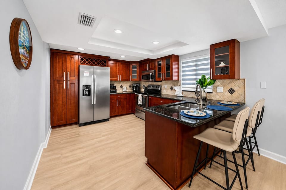 Fully equipped kitchen with stainless steel appliances, granite countertops, a breakfast bar, and ample space for preparing meals during your stay.