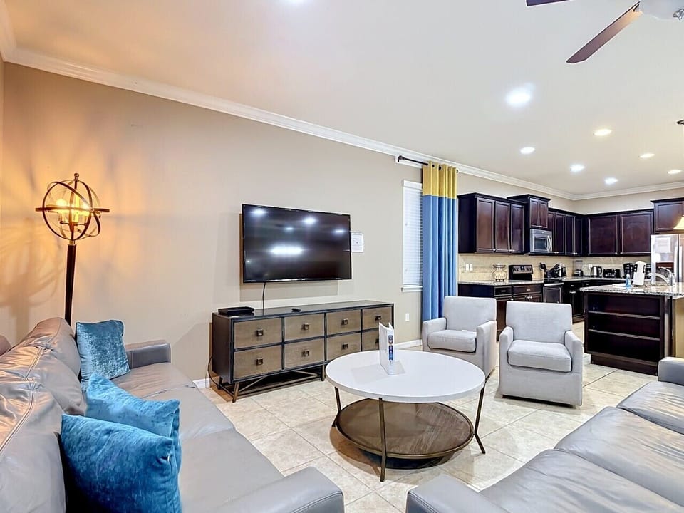 Spacious living room with comfortable seating, large smart TV, and open access to the gourmet kitchen.