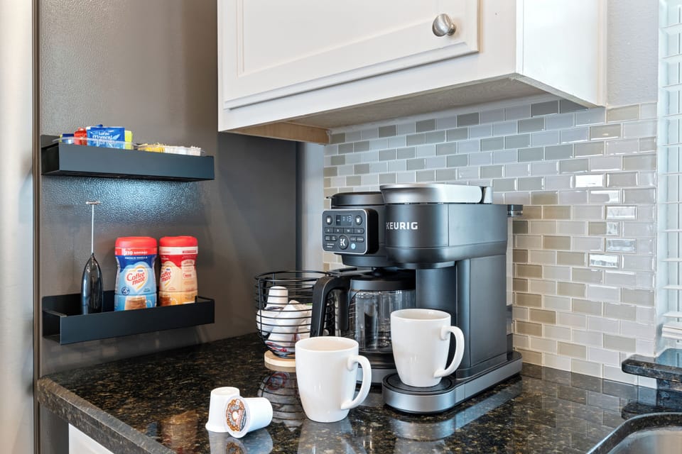 Modern kitchen coffee station with Keurig, mugs, and stocked essentials