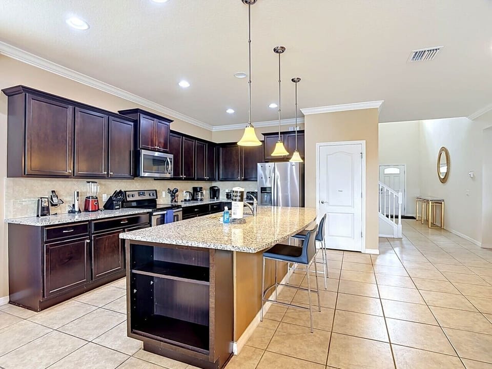 The fully equipped kitchen features generous counter space, modern appliances, and a large island that`s perfect for gathering, dining, and preparing meals together.