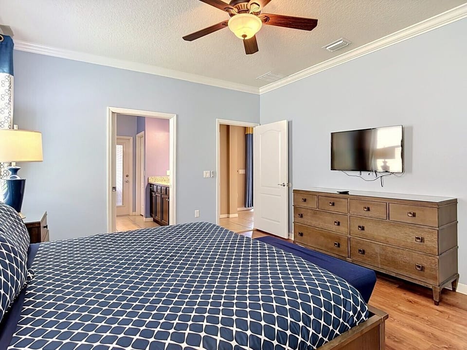 Spacious king bedroom featuring a flat-screen TV, dresser, and en-suite bathroom access.
