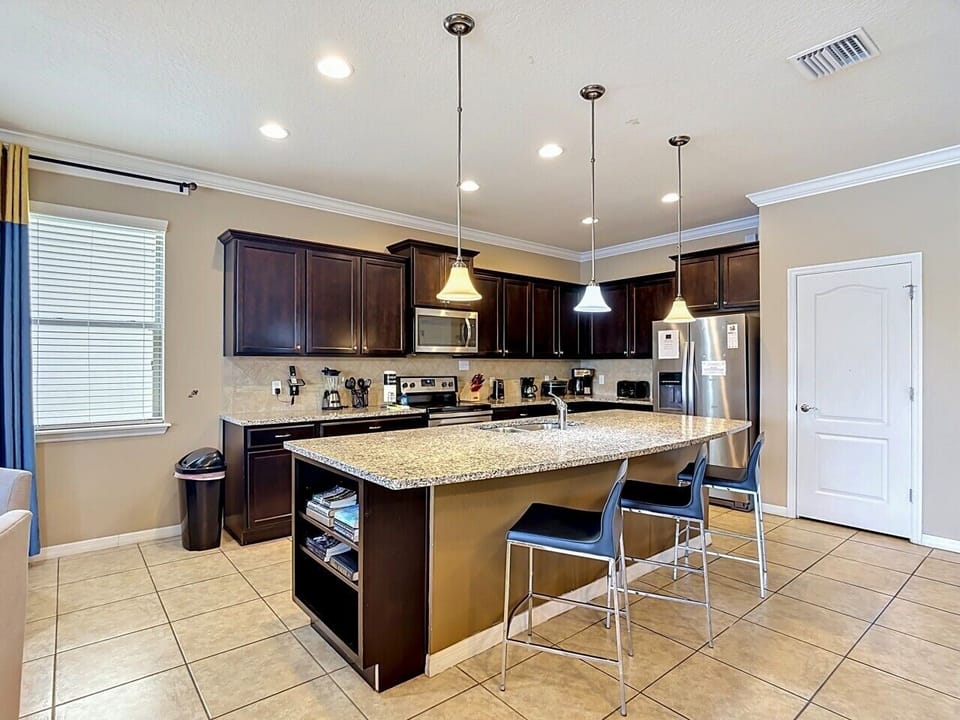 Modern kitchen with granite countertops, breakfast bar, and stainless-steel appliances.