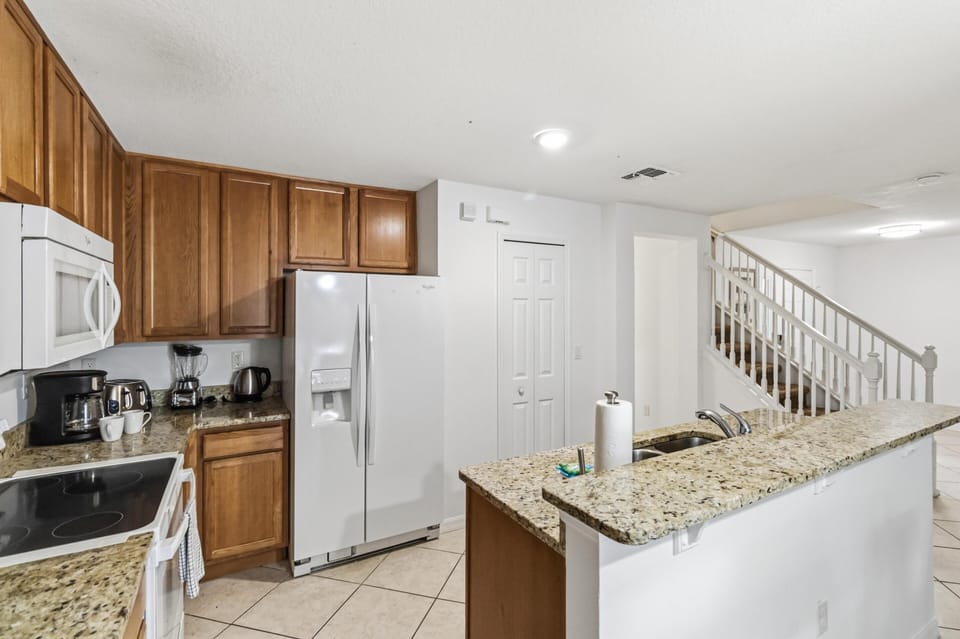 White appliances complement warm oak cabinets and speckled granite counters in the kitchen.