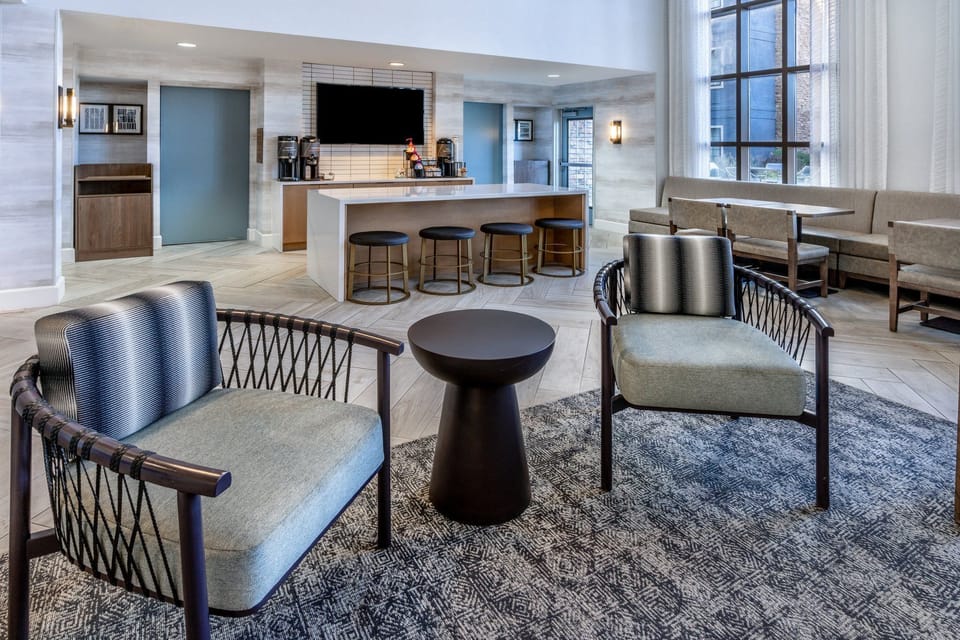 Lobby seating with upholstered chairs and large picture windows facing the street