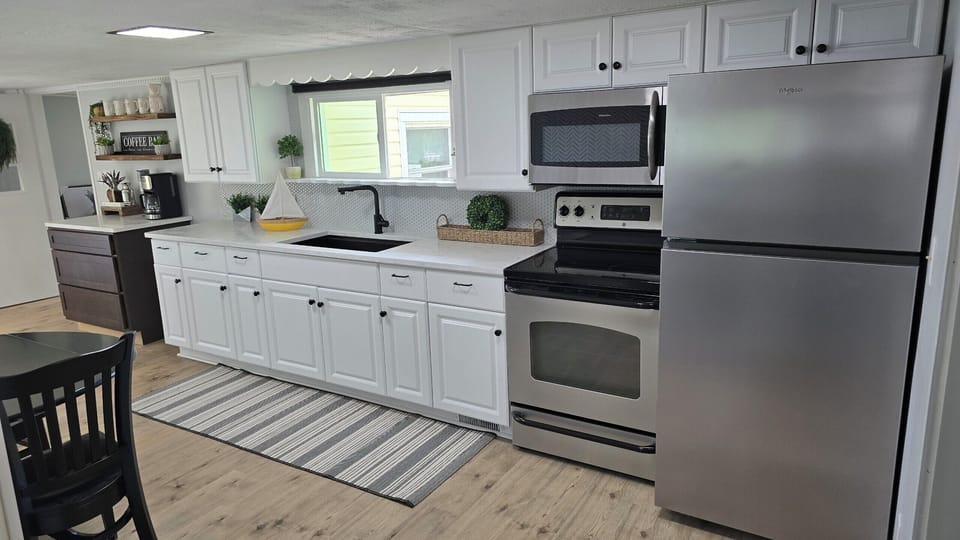 Kitchen with oven, refrigerator, stovetop and coffee bar.