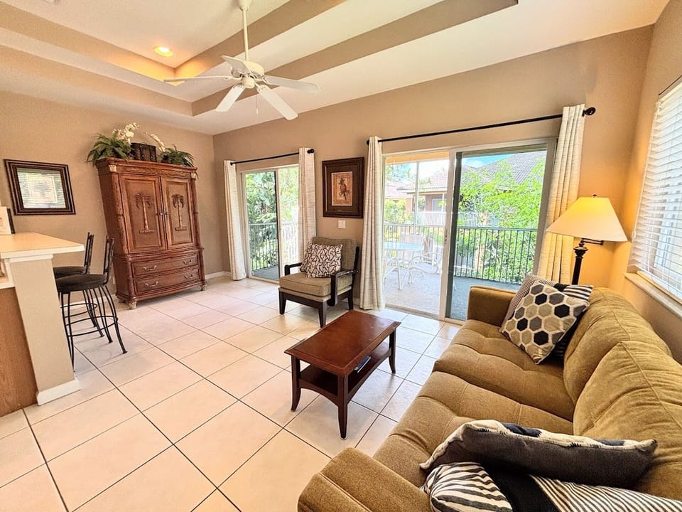 Open living area with comfortable seating, tile flooring, breakfast bar seating, and access to the screened balcony.