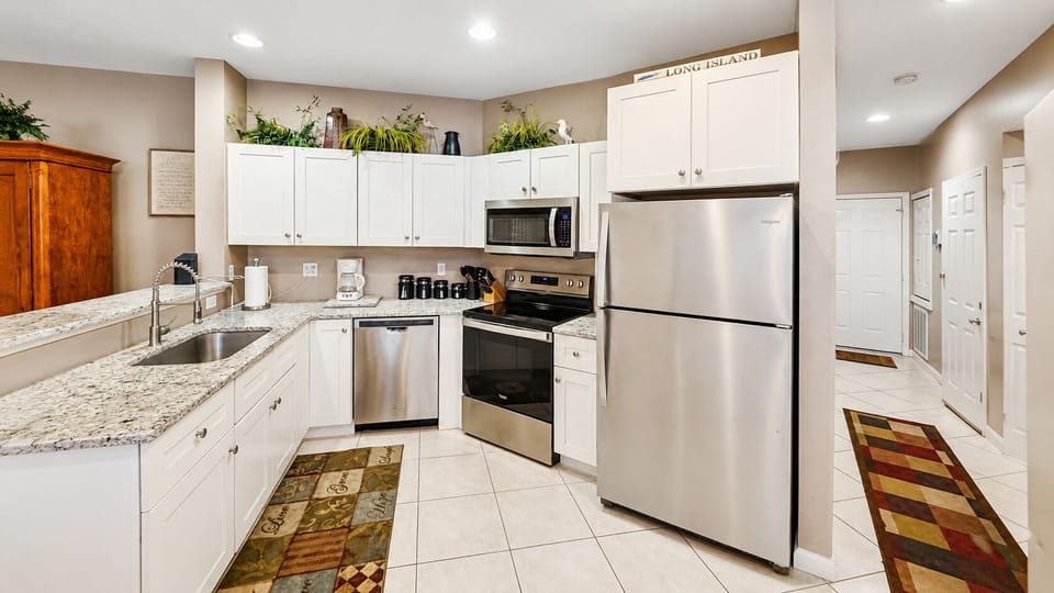 Updated kitchen with white cabinetry, granite countertops, stainless steel appliances, and a bright functional layout.