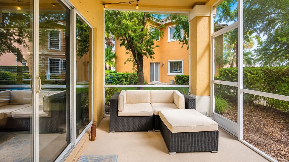 Relaxing screened patio with outdoor lounge seating and a quiet garden-style setting.