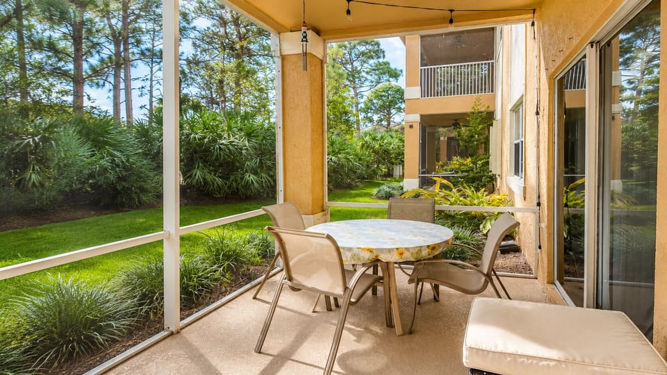 Private screened patio with outdoor dining space and peaceful views of the surrounding greenery.