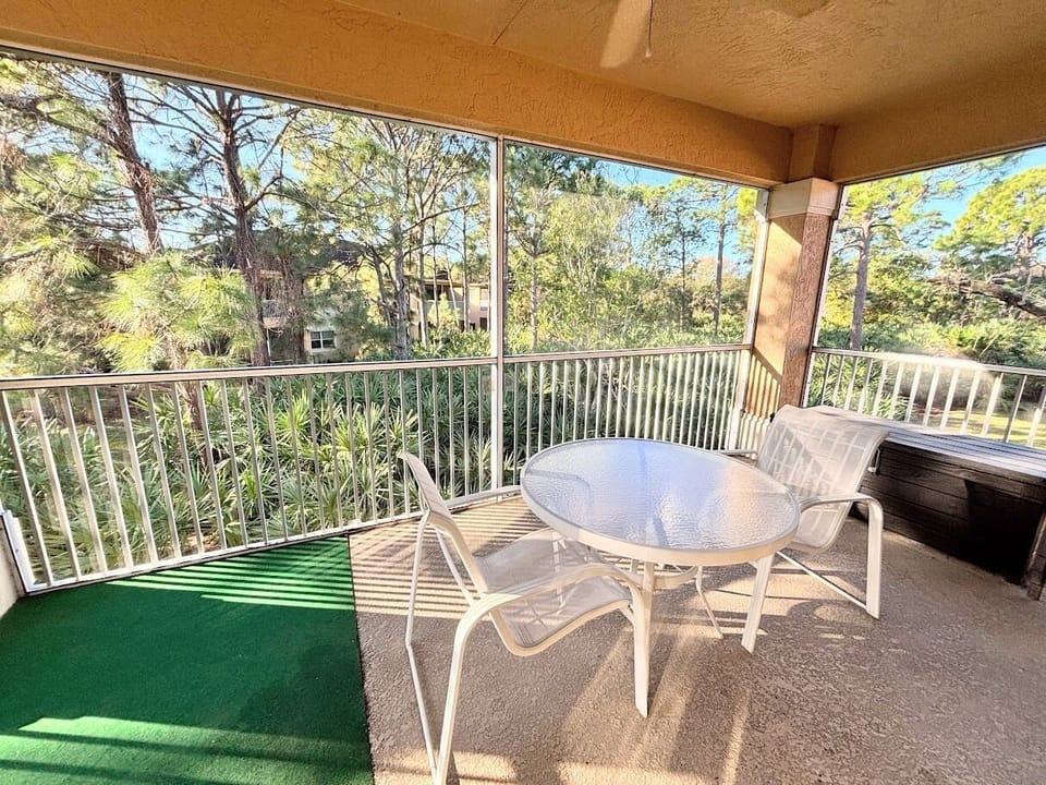 Private screened balcony with outdoor seating and peaceful views of the surrounding trees — a perfect spot for morning coffee or evening relaxation.