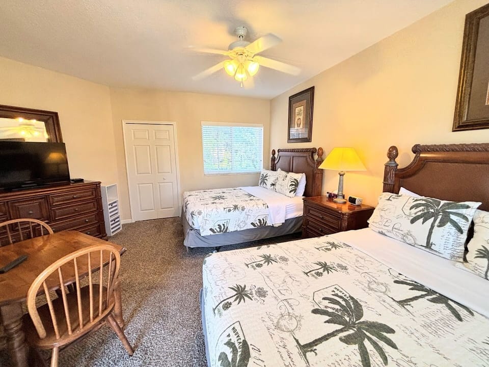 Spacious bedroom with two beds, dresser storage, TV, and a small table with seating.