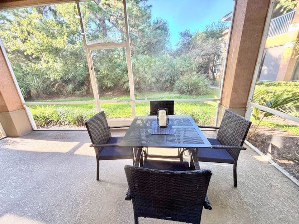 Private screened patio with outdoor dining space and peaceful garden views — perfect for enjoying morning coffee or relaxing outdoors.