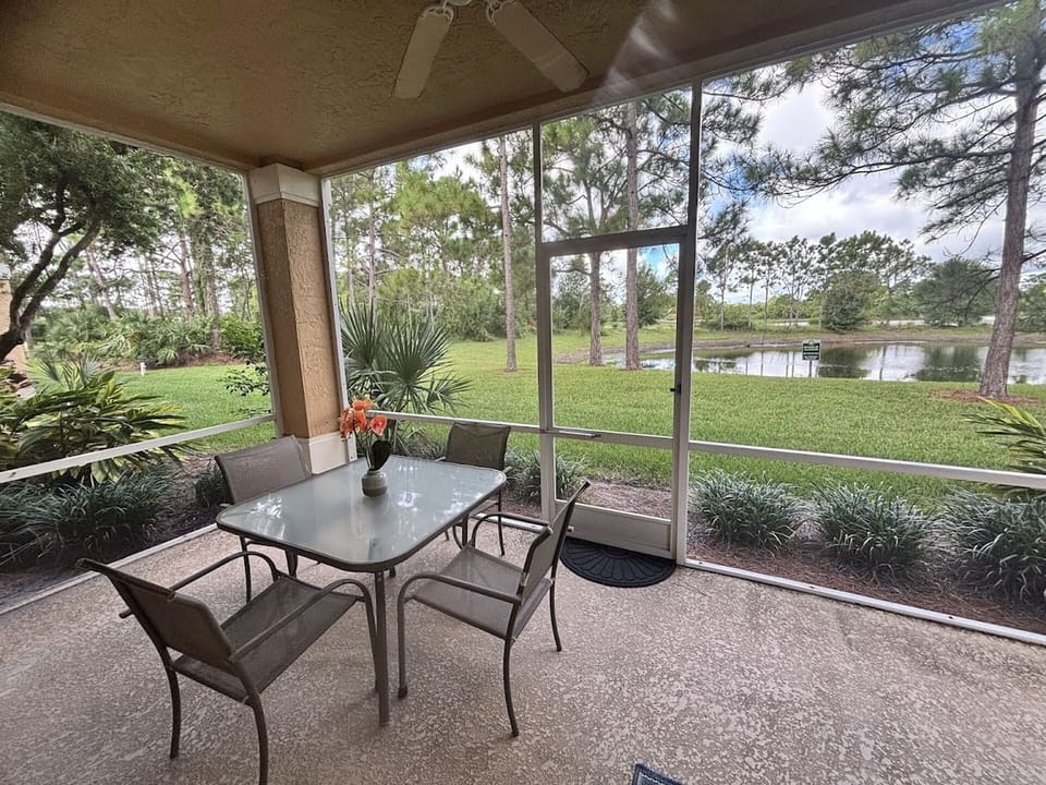 Private screened patio with outdoor seating and peaceful views of the green space and water.