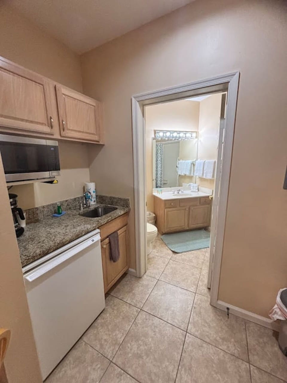 Convenient kitchenette area with microwave, mini fridge, sink, and easy access to the bathroom.