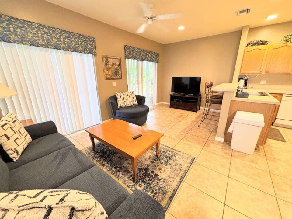 Comfortable living area with cozy seating, tile flooring, large TV, and easy access to the kitchen.