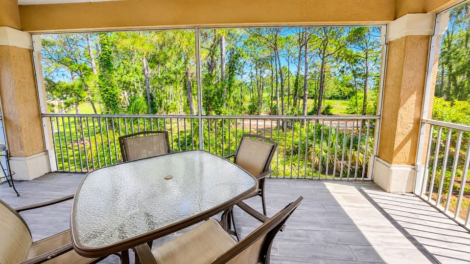 Private screened balcony with outdoor seating and peaceful views of the surrounding trees.