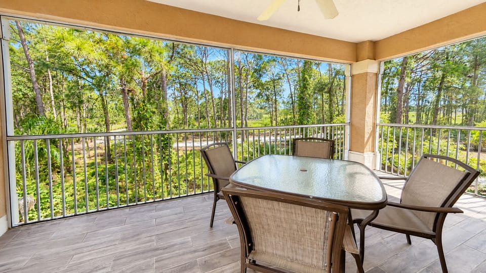 Spacious screened balcony with outdoor dining space and relaxing wooded views.