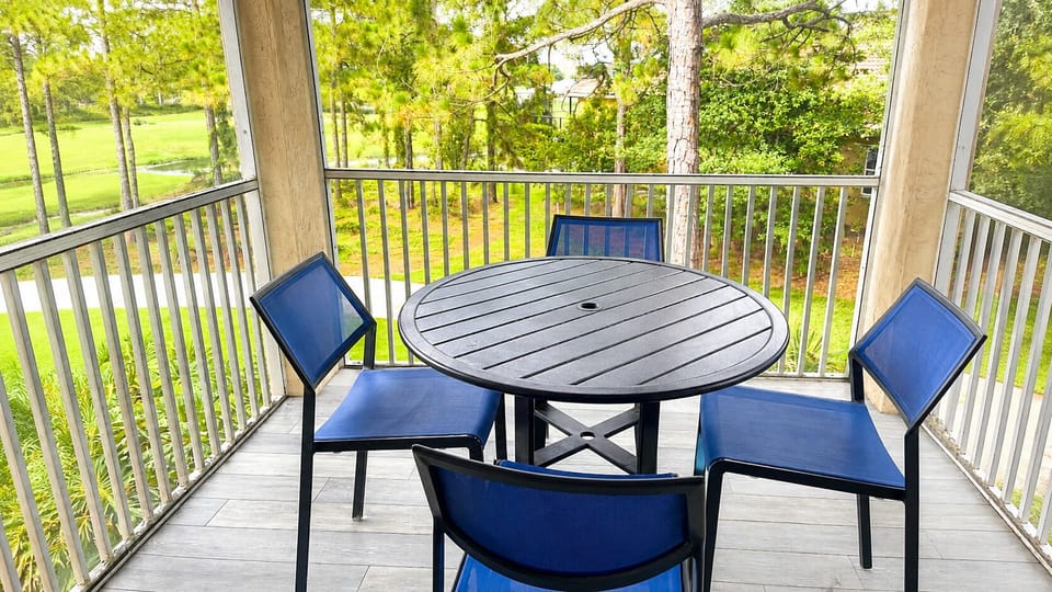 Private screened balcony with outdoor seating and peaceful views of the surrounding greenery.