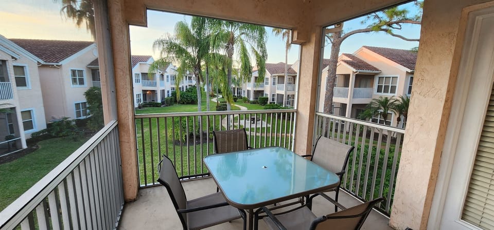 Private screened balcony with outdoor dining space and peaceful views of the surrounding community grounds.