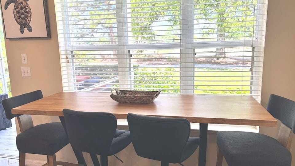 Bright dining area with a large table, modern seating, and peaceful views through the wide windows.